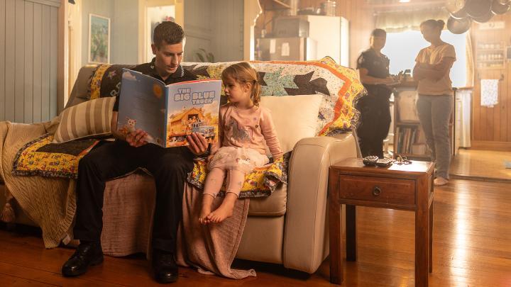 officer reading to child while another officer talks to adults in the background