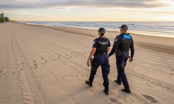 police officers walk along beach
