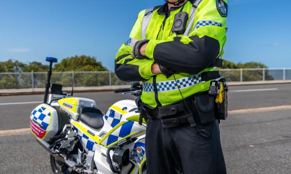 QPS highway patrol officer standing with police motorcycle