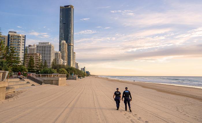 Queensland police officers walk along a Gold Coast beach at sunrise