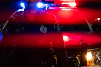 Qld police officer in front of vehicle with flashing lights at night