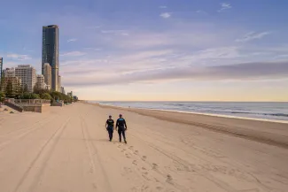 police officers walk along gold coast beach at sunrise