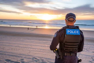 police officer facing sunrise on beach