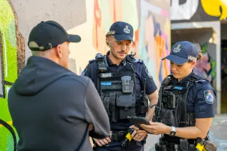 police officers talking to person while viewing qlite tablet